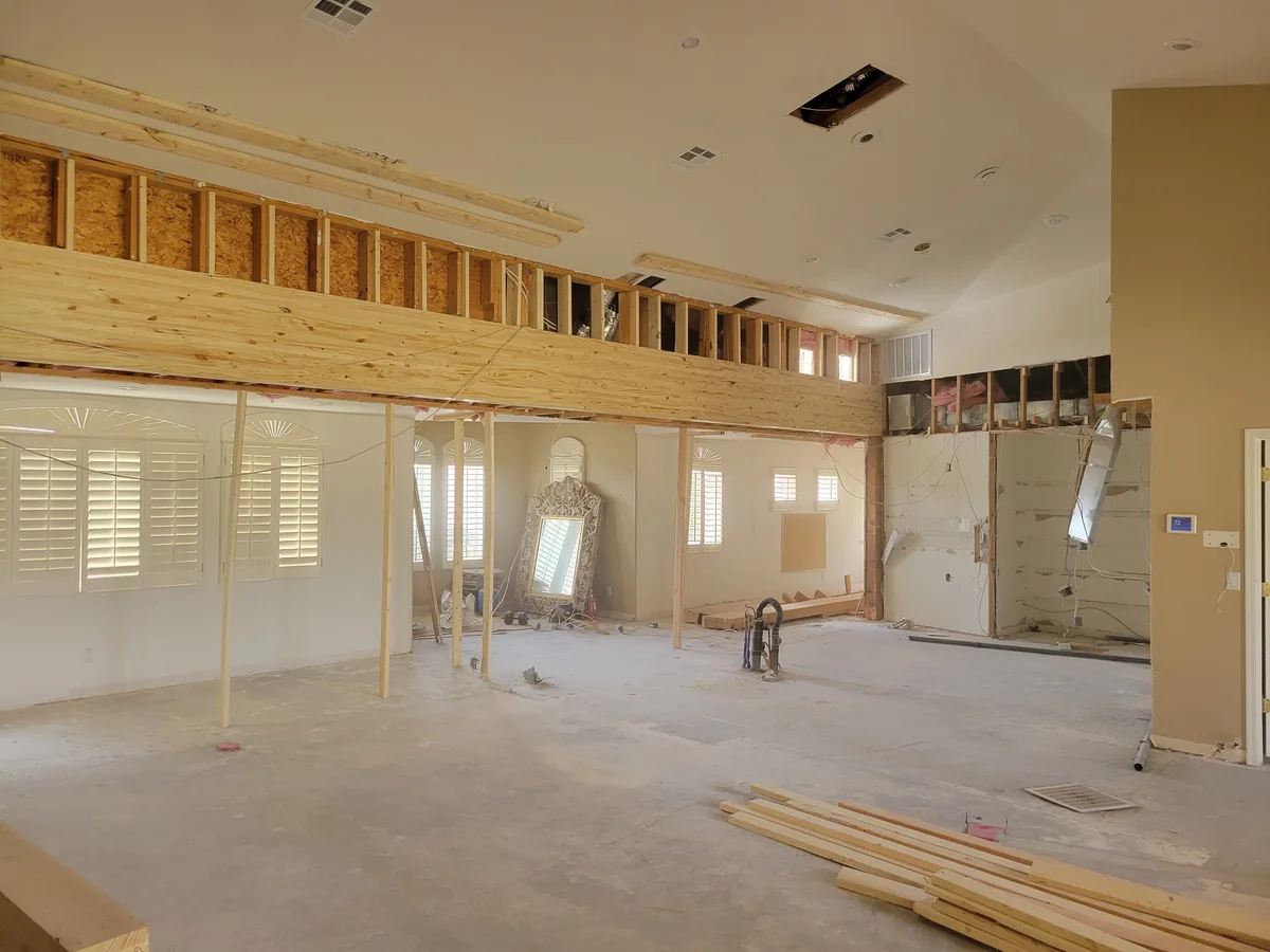 Interior remodeling work with exposed wall framing and drywall removed around a large room