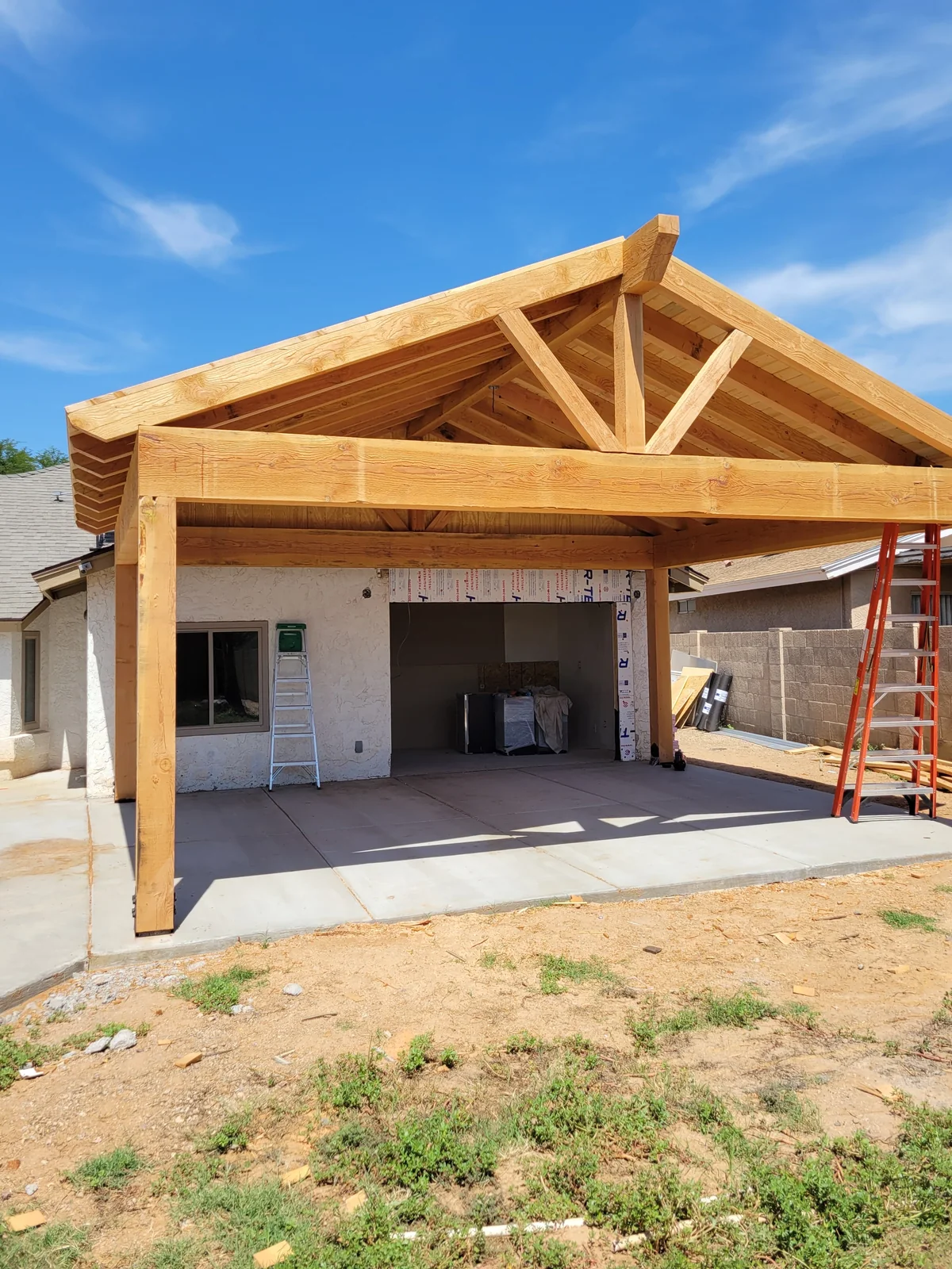 Concrete patio slab beneath a timber-framed patio cover during construction
